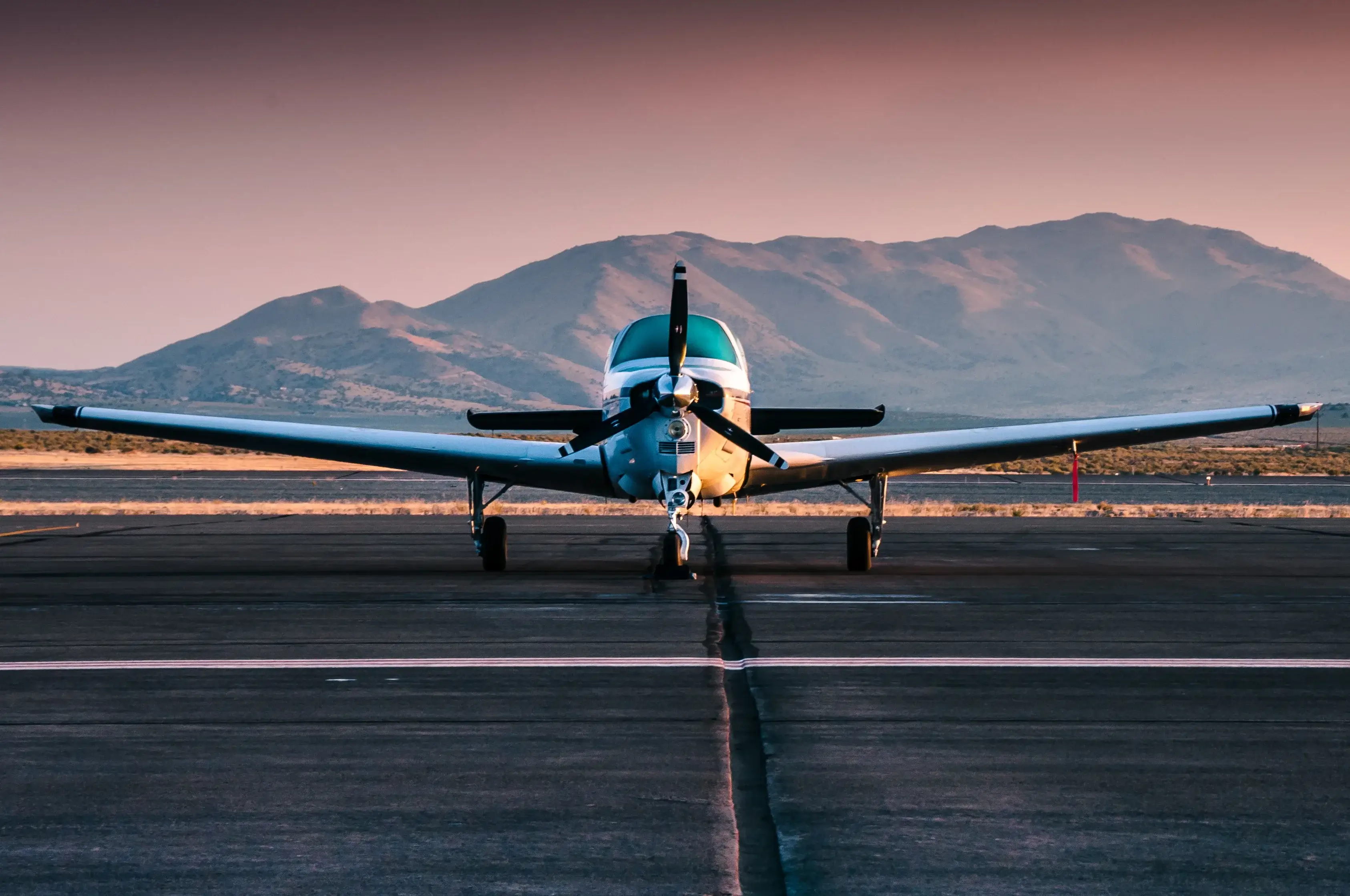 Single Engine Plane Landing On Runway With Mountain In Foreground
